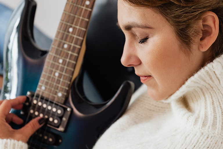 Women Holding Electric Guitar - Featured Image