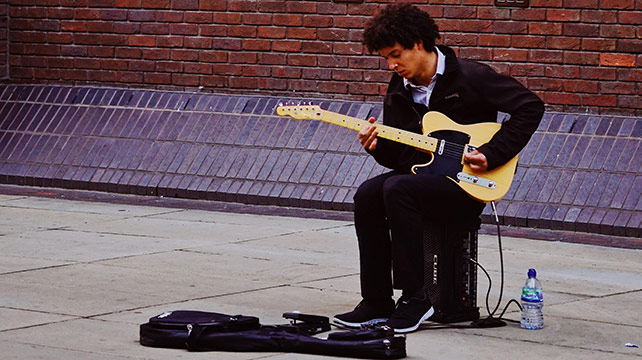 Man playing electric guitar through a battery-powered amp